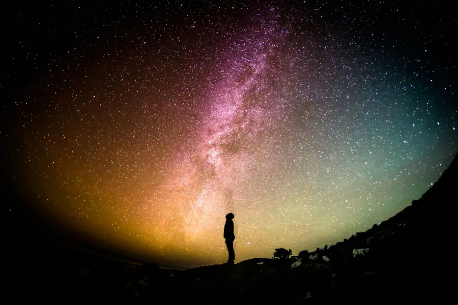 Silhouette of a person standing on a hill under the Milky Way